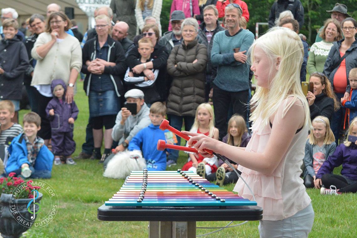 Girl Playing Rainbow Coloured Outdoor Xylophone with Audience