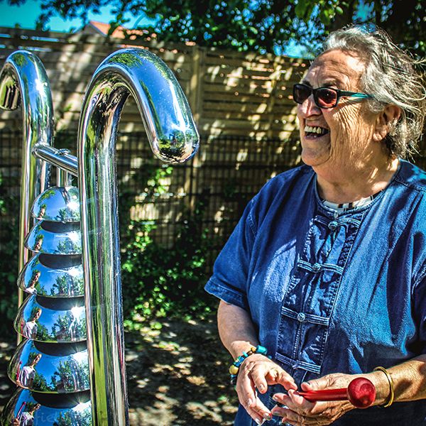 older lady playing a bell lyre outdoor instrument in the sunshine