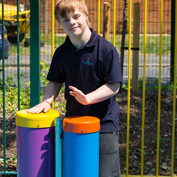 boy with special needs playing colourful outdoor drums in a school playground