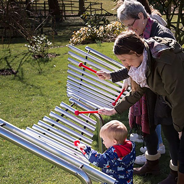 Family playing a large butterfly shaped metallophone in a park