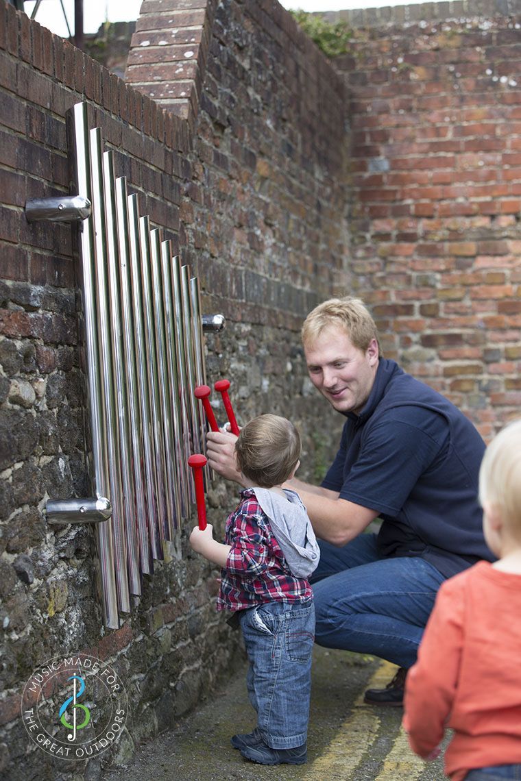 man and baby playing wall mounted mirrored chimes together