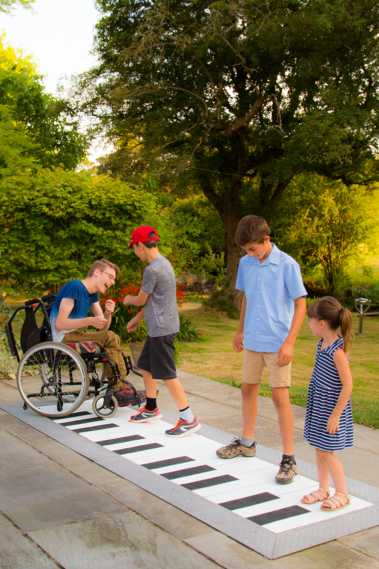 four children playing on a giant floor piano outdoors