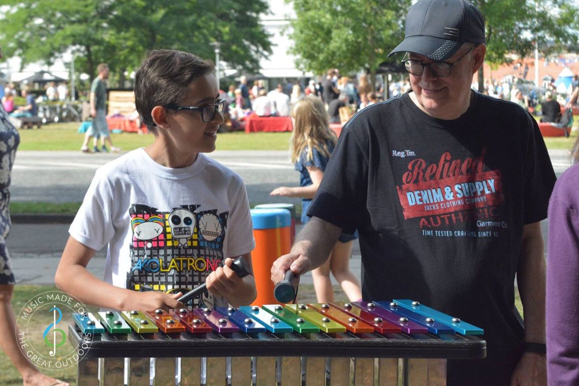 Man and Boy Playing Rainbow Coloured Outdoor Xylophone in Park
