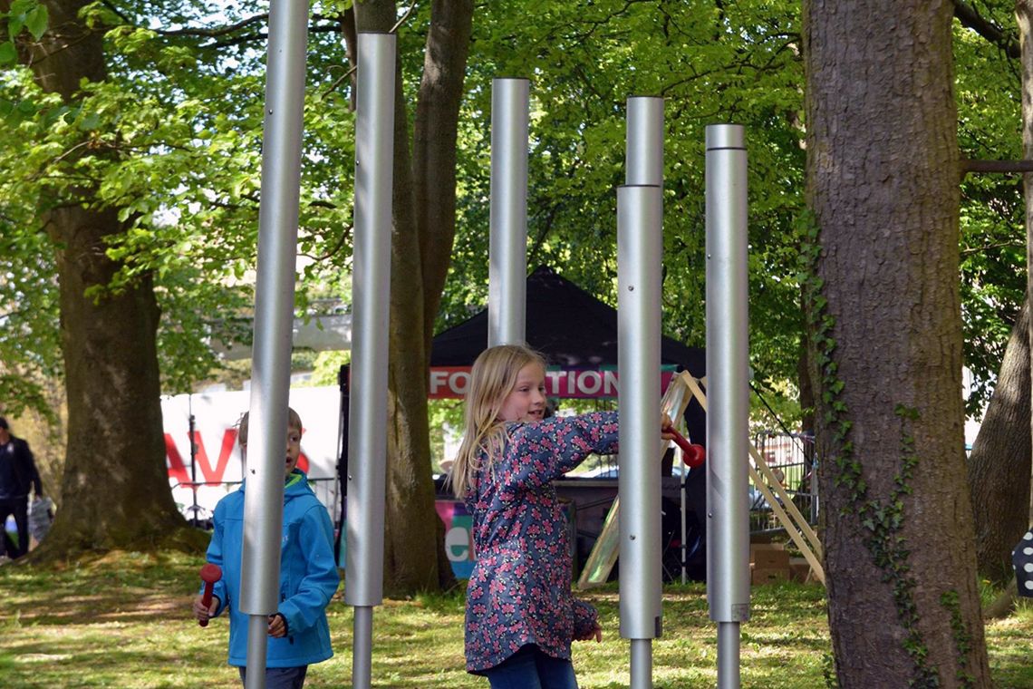 boy and girl playing a large outdoor chimes in a park