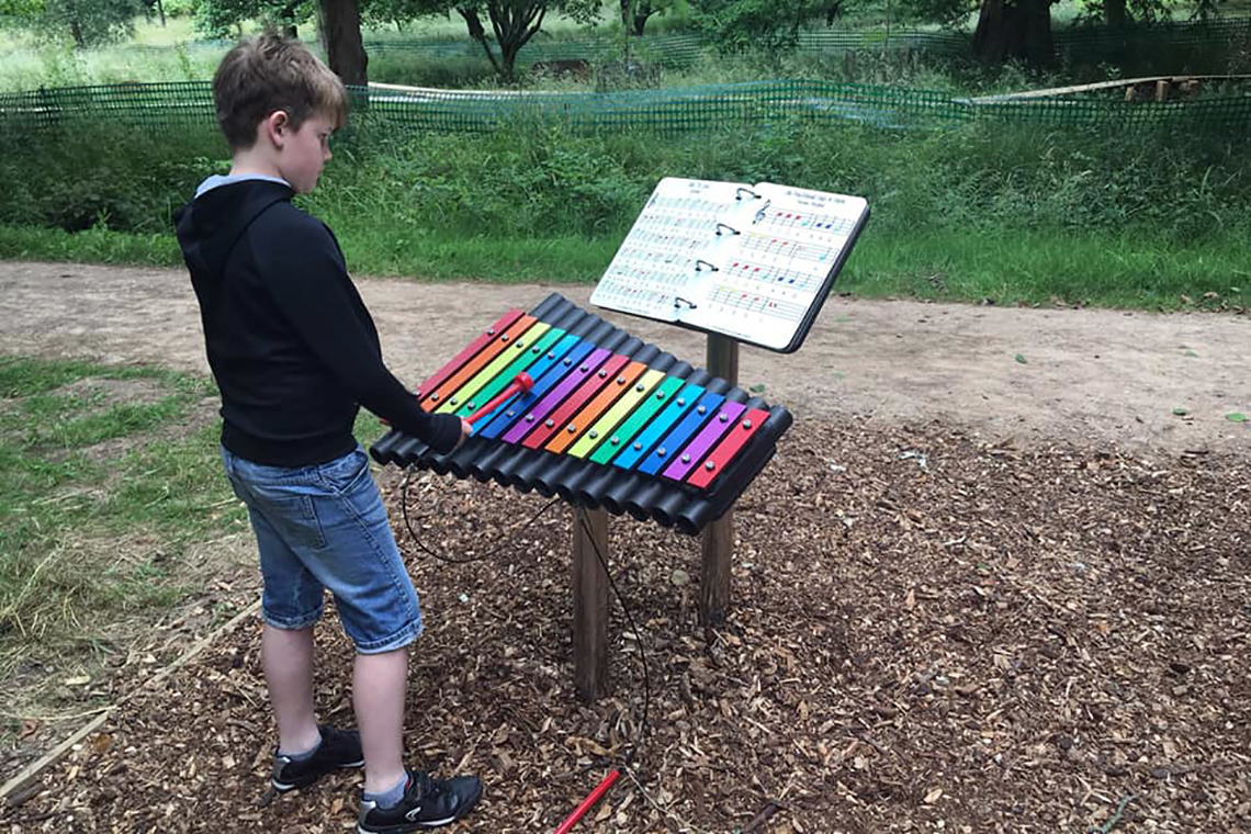 an outdoor xylophone with rainbow coloured notes and an outdoor music book